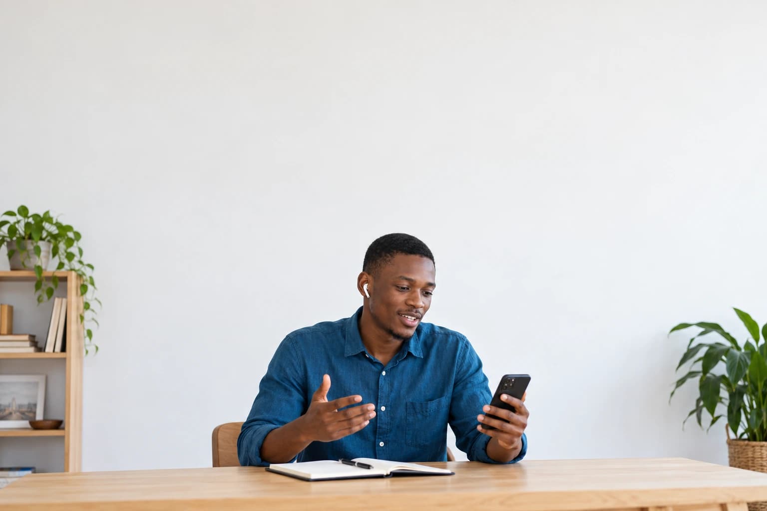 Un homme s’entraîne à un entretien avec son téléphone, assis à son bureau.